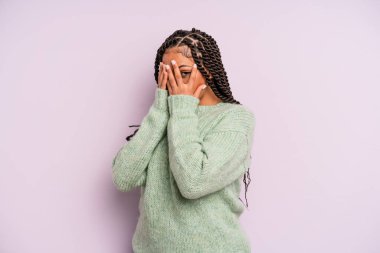 Siyah afro kadın korkmuş ya da utanmış hissediyordu. Gözleri yarı kapalı ya da elleri kapalı dikizliyordu.