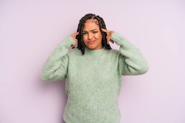 Siyah afro kadın konsantre olmuş ve bir fikir üzerinde kafa yoruyor, bir soruna ya da soruna bir çözüm hayal ediyor.