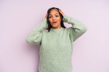 Siyah afro kadın el ele tutuşuyor, ağzı açık, son derece şanslı, şaşırmış, heyecanlı ve mutlu.