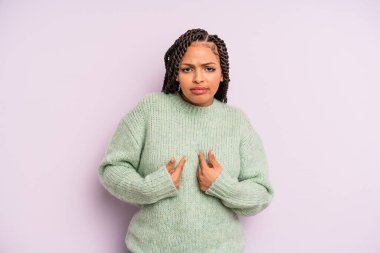 Siyah afro kadın, şaşkın ve şaşkın bakışlarıyla kendini işaret ediyor. Seçildiğine şaşırmış ve şaşırmış.