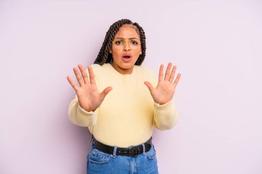 Siyah afro kadın korkmuş, geri çekiliyor ve korku ve panik içinde çığlık atıyor, kabusa tepki veriyor.