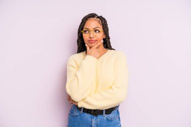 Siyah afro kadın ciddi, düşünceli ve güvensiz görünüyor, bir kolu çapraz ve çene üzerinde, seçenekleri tartıyor