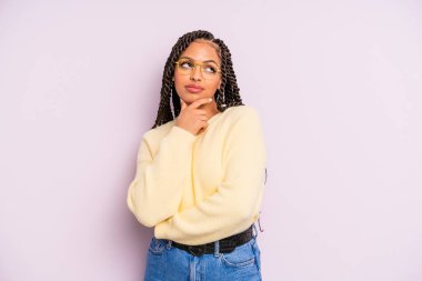 Siyah afro kadın düşünceli, meraklı ya da hayal kuruyor, hayal kuruyor ve uzayı kopyalamak için yukarı bakıyor.