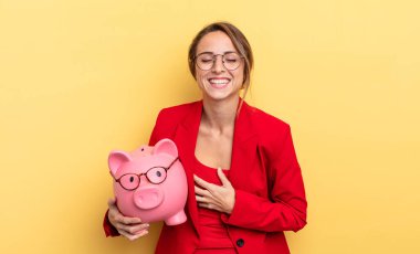 businesswoman laughing out loud at some hilarious joke. piggy bank concept
