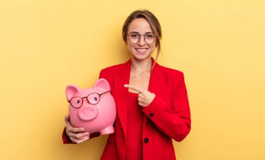 businesswoman looking excited and surprised pointing to the side. piggy bank concept