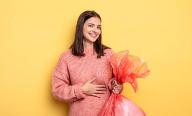 pretty woman laughing out loud at some hilarious joke. trash bag concept