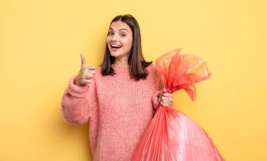 pretty woman feeling proud,smiling positively with thumbs up. trash bag concept