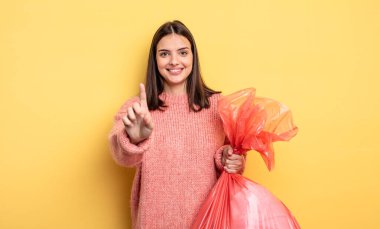 pretty woman smiling proudly and confidently making number one. trash bag concept