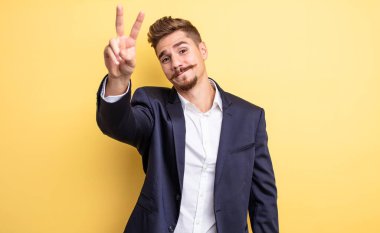 Gülümseyen ve mutlu görünen işadamı, zafer ya da barış işareti yapıyor.