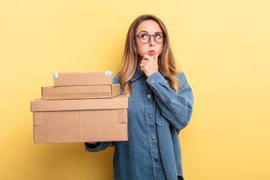 pretty woman thinking, feeling doubtful and confused. package boxes concept