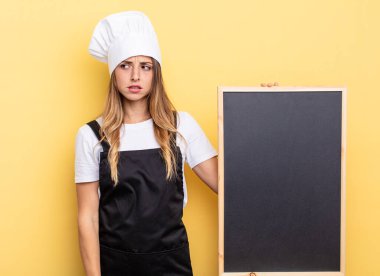 chef woman feeling sad, upset or angry and looking to the side. blackboard menu concept