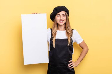 woman artist smiling happily with a hand on hip and confident empty canvas concept