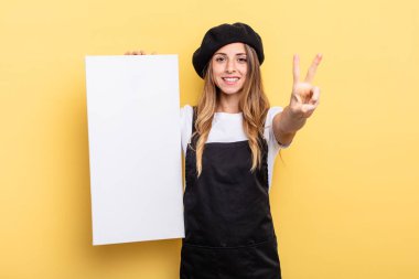 woman artist smiling and looking happy, gesturing victory or peace empty canvas concept