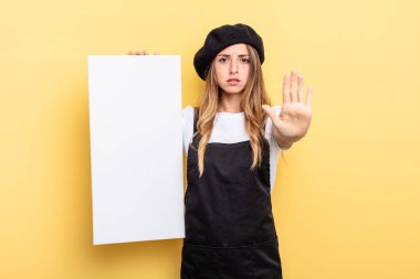 woman artist looking serious showing open palm making stop gesture empty canvas concept
