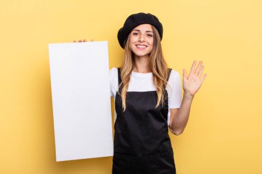 woman artist smiling happily, waving hand, welcoming and greeting you empty canvas concept