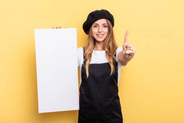 woman artist smiling and looking friendly, showing number one empty canvas concept