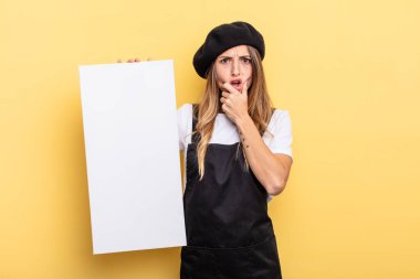 woman artist with mouth and eyes wide open and hand on chin empty canvas concept