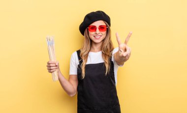 Ressam gülümsüyor ve arkadaş canlısı görünüyor.