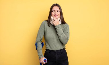 pretty woman smiling with a happy, confident expression with hand on chin. accident injured concept