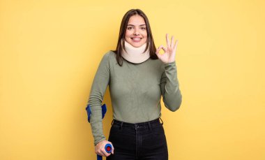 pretty woman feeling happy, showing approval with okay gesture. accident injured concept