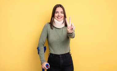 pretty woman smiling and looking happy, gesturing victory or peace. accident injured concept