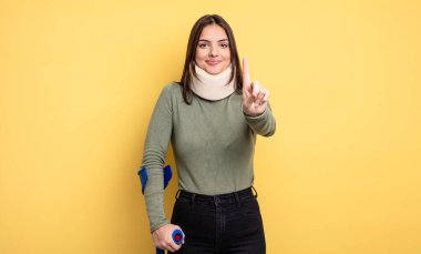 pretty woman smiling proudly and confidently making number one. accident injured concept