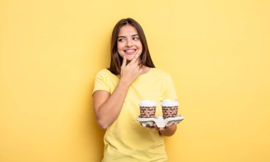 pretty woman smiling with a happy, confident expression with hand on chin. take away coffee concept