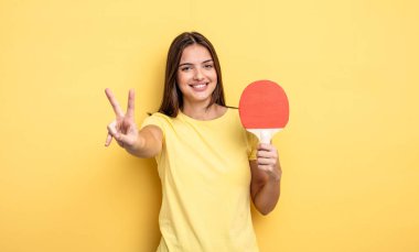pretty woman smiling and looking happy, gesturing victory or peace. ping pong concept