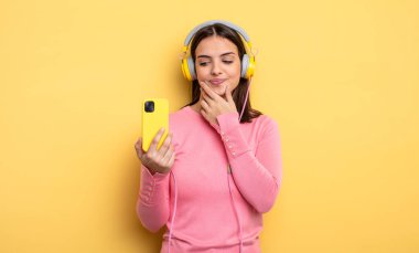 pretty woman smiling with a happy, confident expression with hand on chin. listening music concept