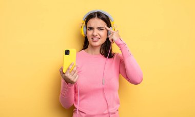 pretty woman feeling confused and puzzled, showing you are insane. listening music concept