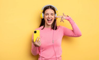 pretty woman looking unhappy and stressed, suicide gesture making gun sign. listening music concept