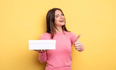 pretty woman feeling proud,smiling positively with thumbs up. white box packaging concept