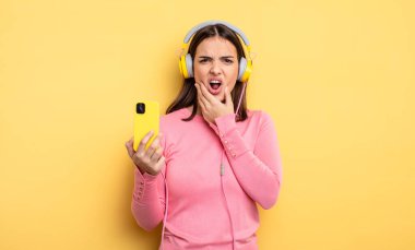 pretty woman with mouth and eyes wide open and hand on chin. listening music concept