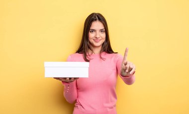 pretty woman smiling proudly and confidently making number one. white box packaging concept