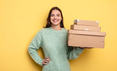 pretty woman smiling happily with a hand on hip and confident packages boxes concept