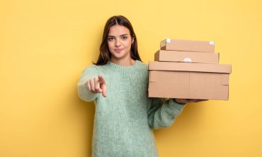 pretty woman pointing at camera choosing you packages boxes concept
