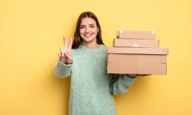 pretty woman smiling and looking happy, gesturing victory or peace packages boxes concept
