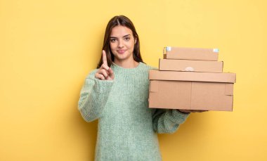 pretty woman smiling proudly and confidently making number one packages boxes concept