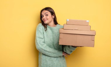 pretty woman shrugging, feeling confused and uncertain packages boxes concept