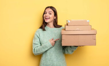 Güzel bir kadın heyecanlı ve şaşırmış görünüyor. Yan paket kutuları kavramına işaret ediyor.