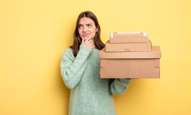 Güzel bir kadın düşünüyor, kuşkulu hissediyor ve kafası karışık paket kutuları konsepti