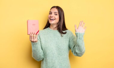 Güzel bir kadın mutlu bir şekilde gülümsüyor, el sallıyor, hoş karşılıyor ve seni selamlıyor. planlayıcı konsepti