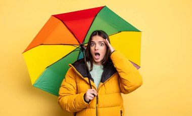 pretty woman feeling stressed, anxious or scared, with hands on head. winter and umbrella concept