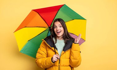 pretty woman feeling happy and astonished at something unbelievable. winter and umbrella concept