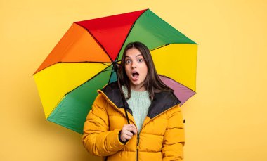 pretty woman looking very shocked or surprised. winter and umbrella concept