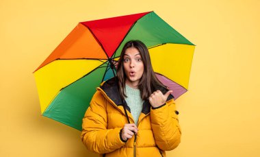 pretty woman looking astonished in disbelief. winter and umbrella concept