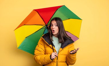 pretty woman amazed, shocked and astonished with an unbelievable surprise. winter and umbrella concept