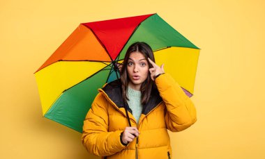 pretty woman looking surprised, realizing a new thought, idea or concept. winter and umbrella concept