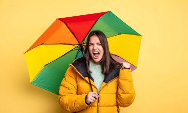 pretty woman shouting aggressively with an angry expression. winter and umbrella concept