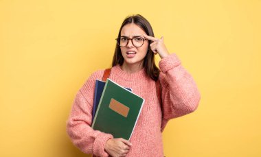 pretty student woman feeling confused and puzzled, showing you are insane